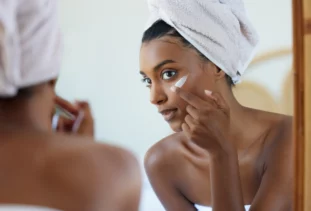 Woman applying exfoliating skin care with a combination of AHA and BHAs.