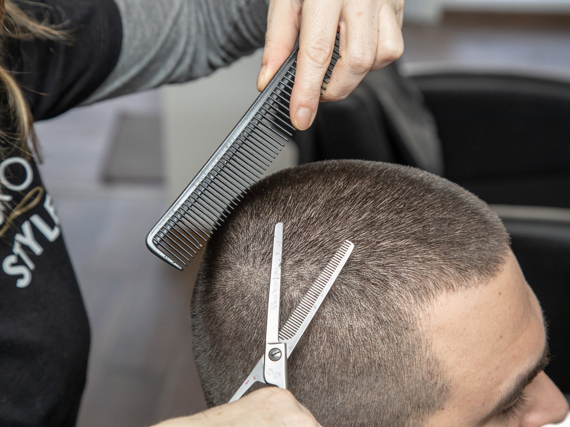 A grooming professional cutting a client's hair with shears.