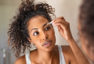 woman shaping eyebrows at home