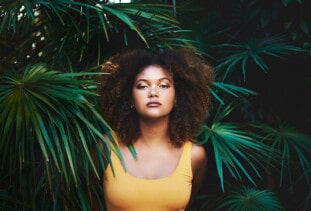 woman with afro in front of foliage