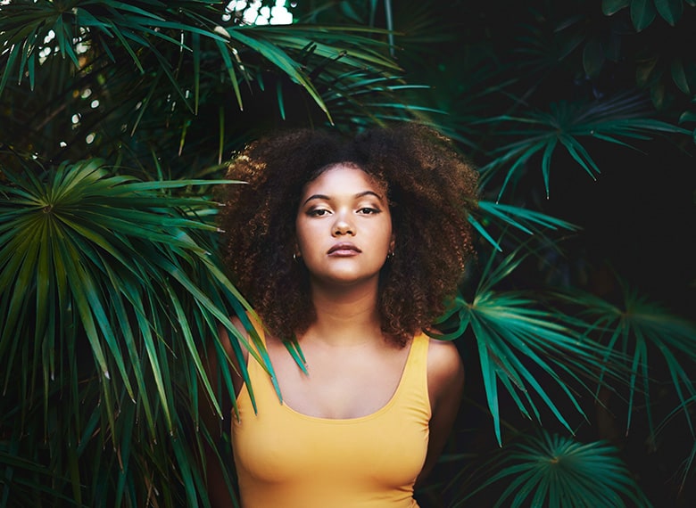 woman with afro in front of foliage