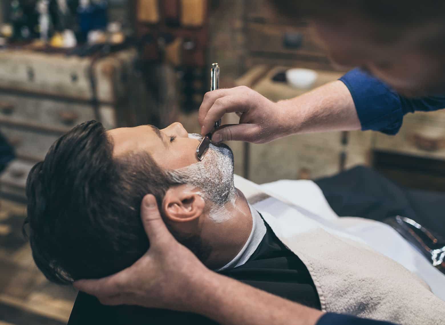 person getting straight razor shave at the barbershop