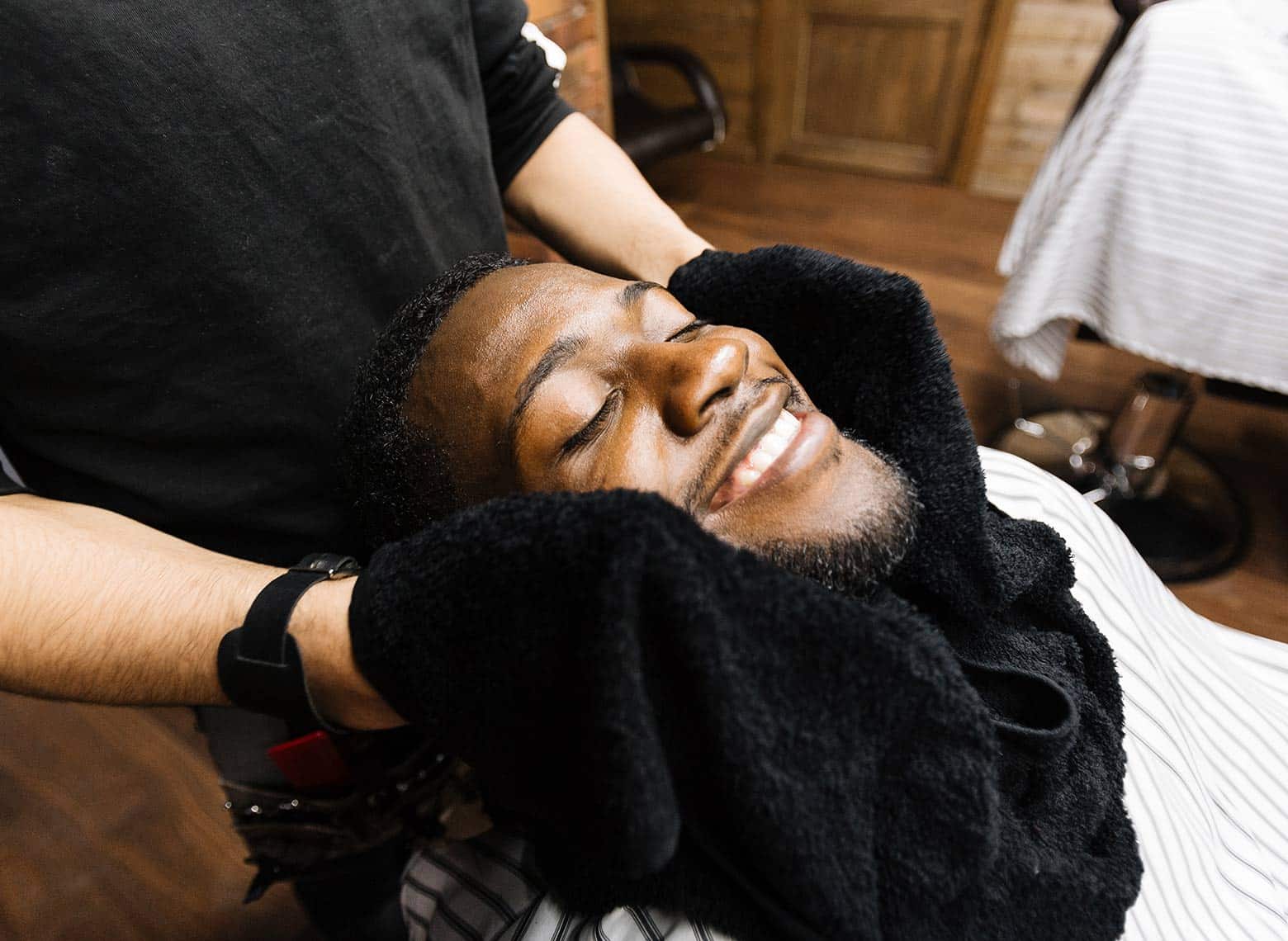 man smiling and getting a hot towel shave