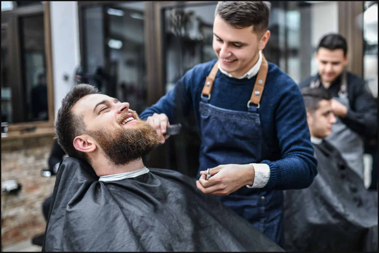man talking with barber while getting a beard trim