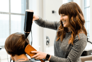 hair stylist blow drying clients hair