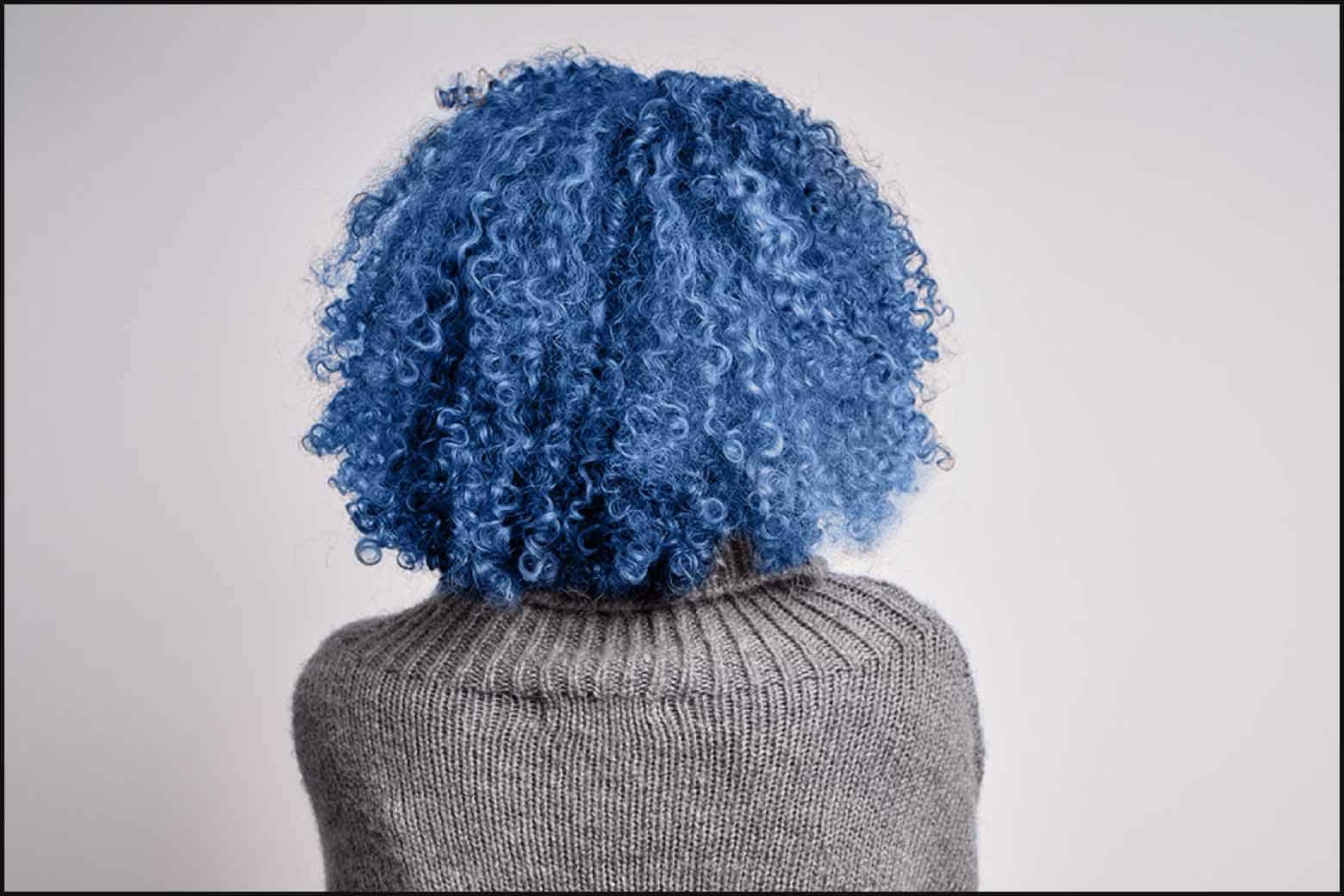 back of a person with curly blue hair and a grey sweater