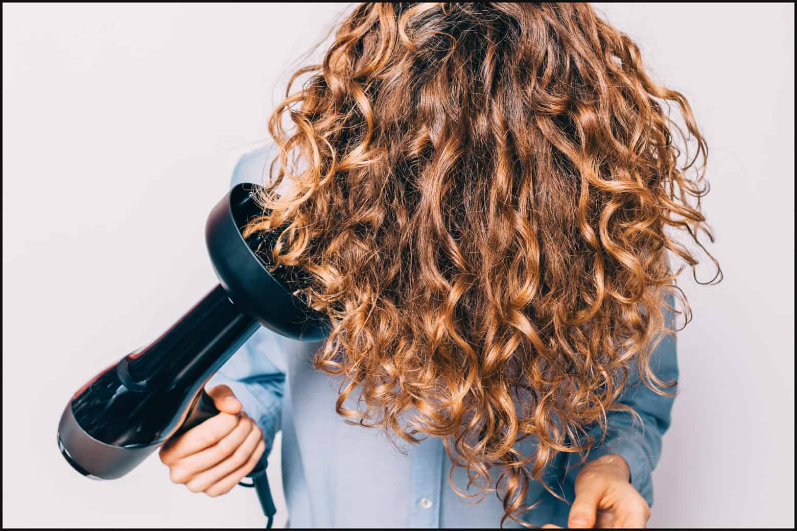 person with light brown curly hair holding head down to dry hair with a blow dryer and diffuser attachment