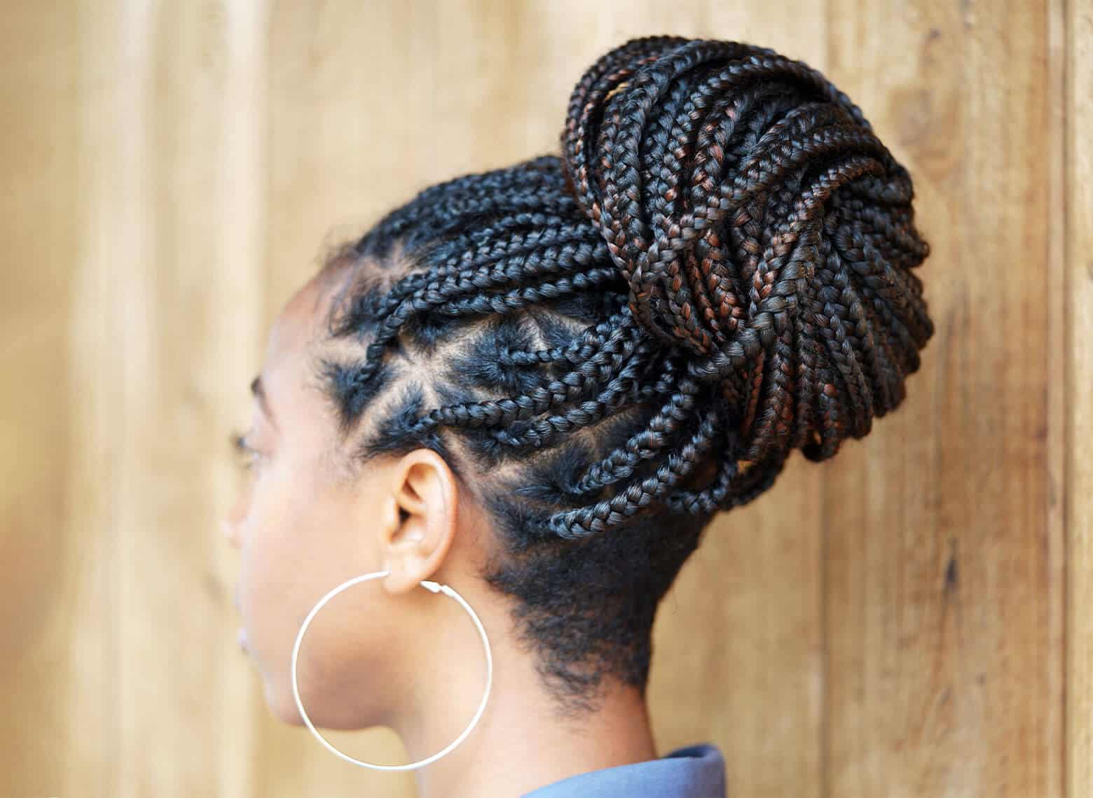 person wearing silver hoop earrings with triangle box braids tied up in a bun