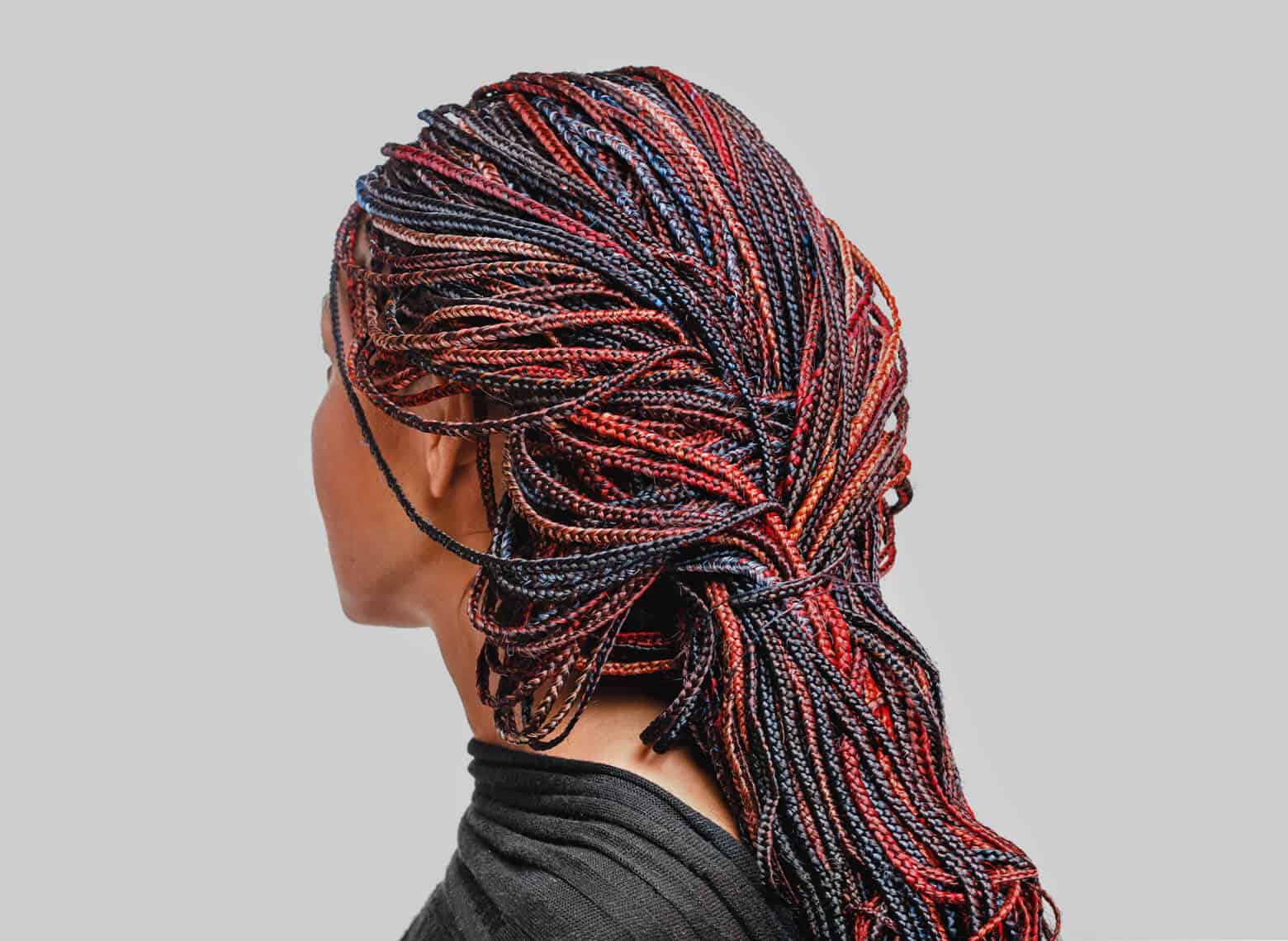 backside of person’s head with long and colorful red, blue, and black microbraids
