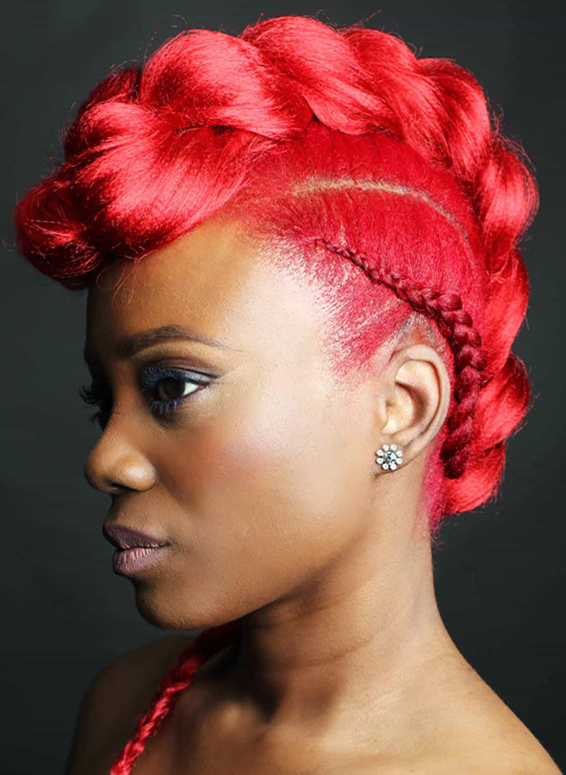 profile of person with bright red braided faux hawk and wearing flower-shaped stud earrings