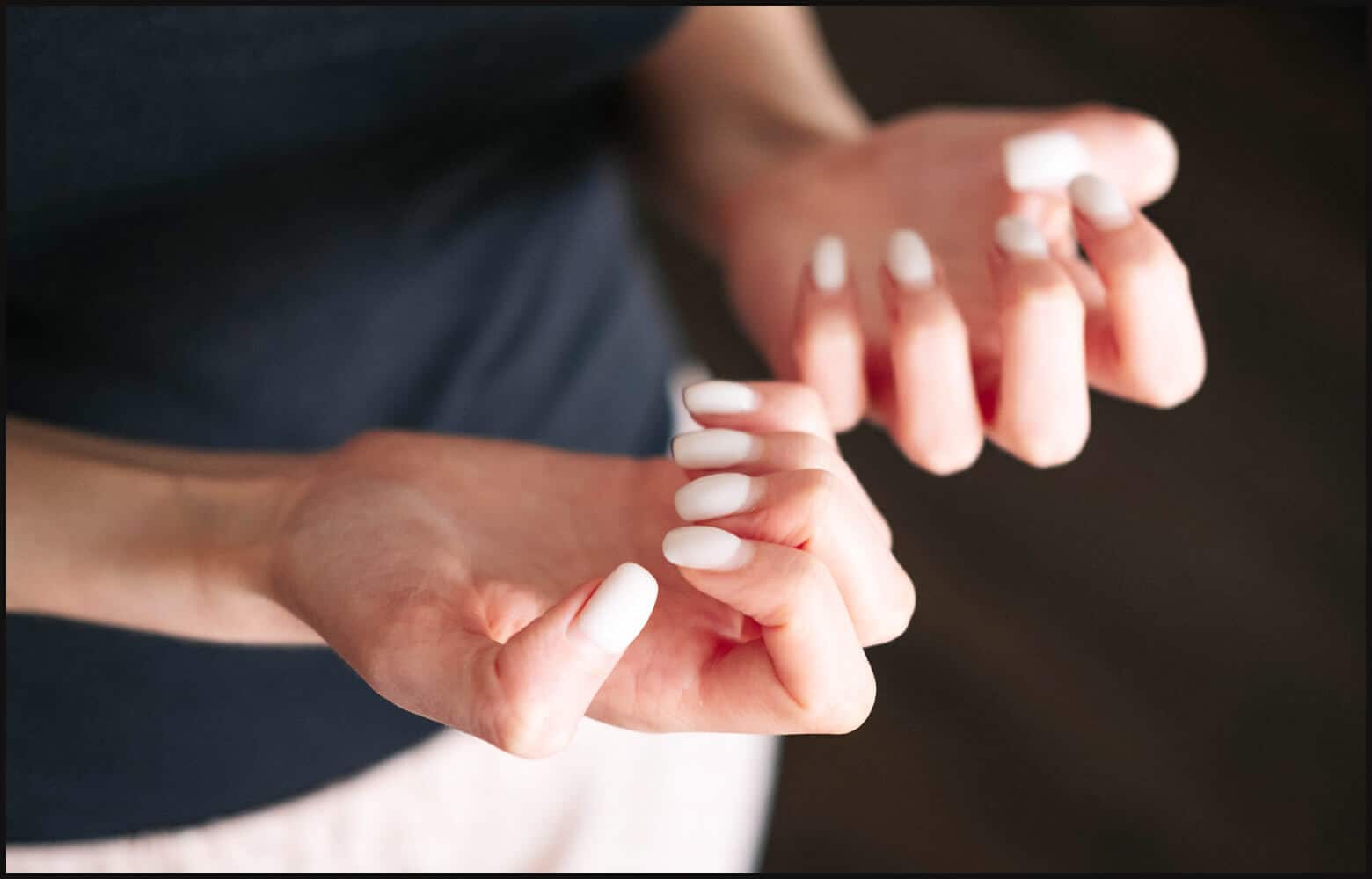 close up on person’s hands with white nail polish