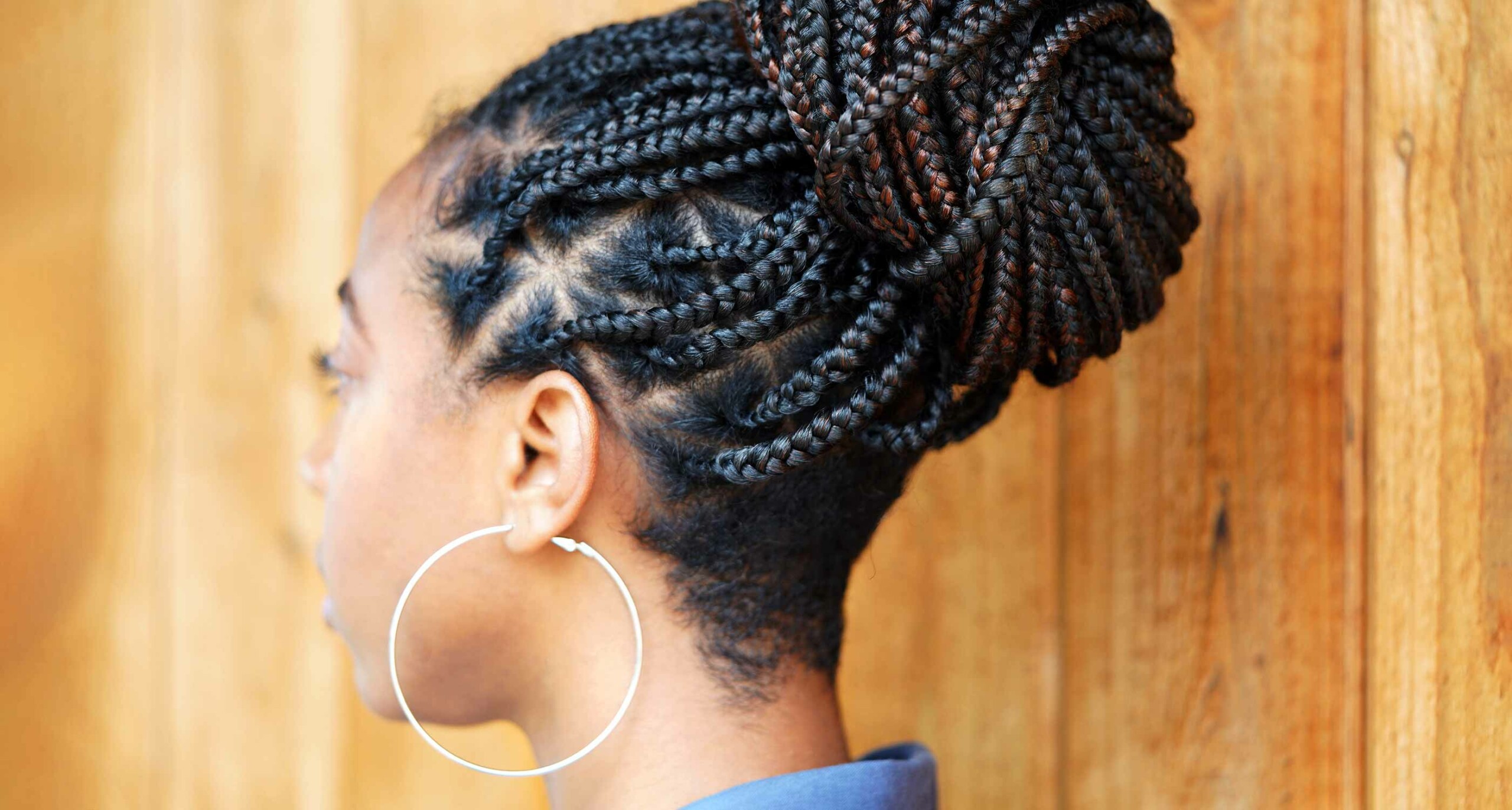 back view of person wearing large hoop earrings and box braids in a bun