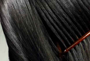 close-up of a red comb combing through black hair