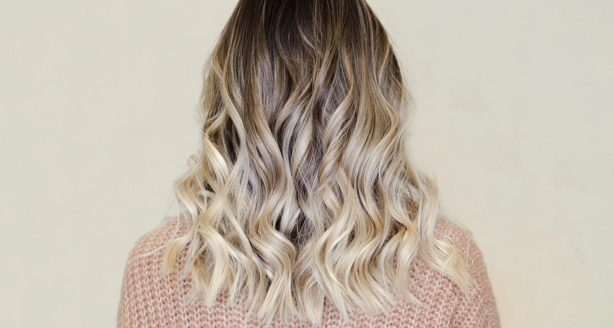 back of head showing wavy brunette and blonde ombre hair, person is wearing a knitted creme sweater
