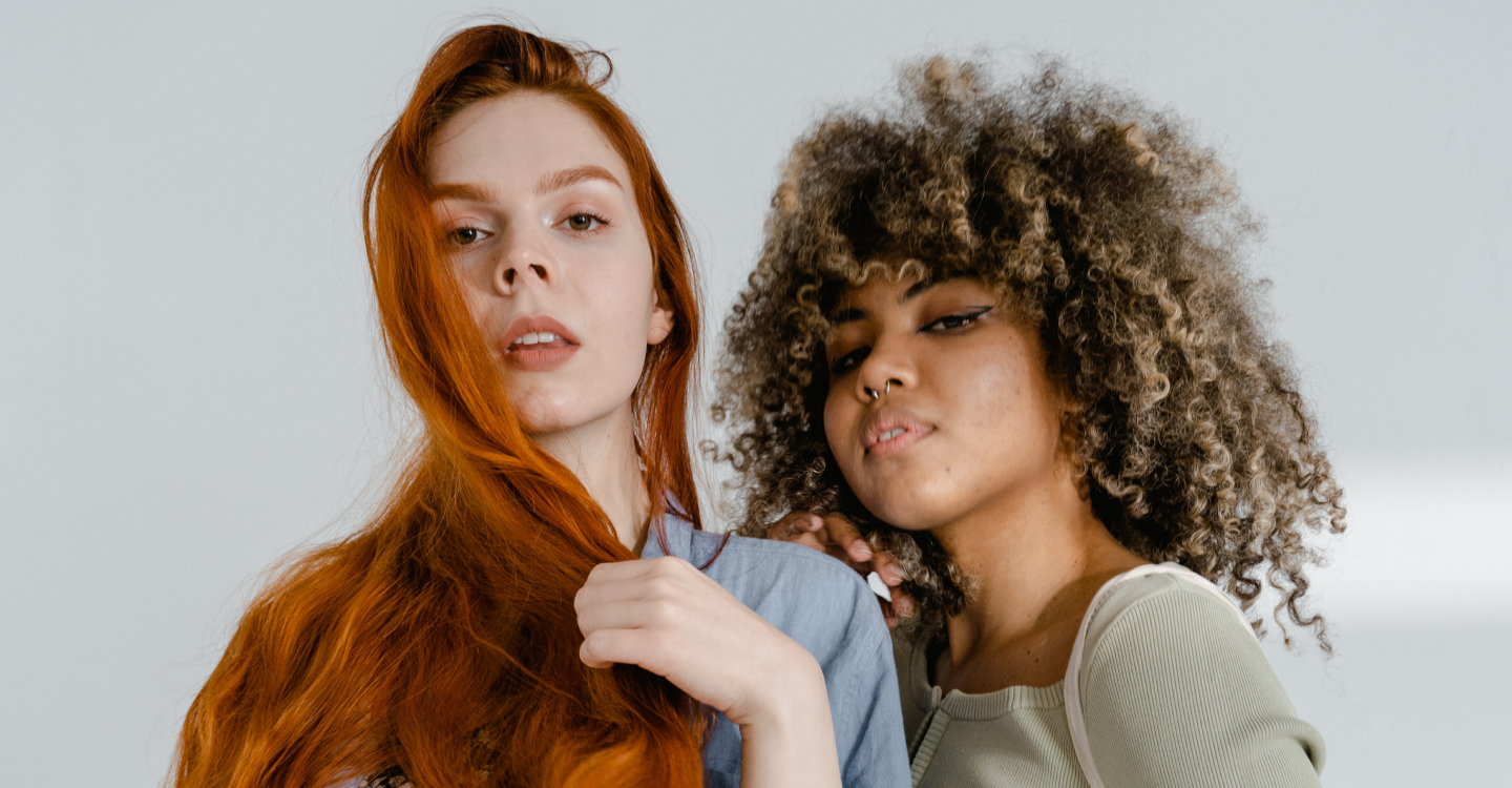 woman with straight red hair and woman with curly brown and blonde hair posing
