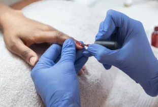 a person getting their nails painted red in a salon