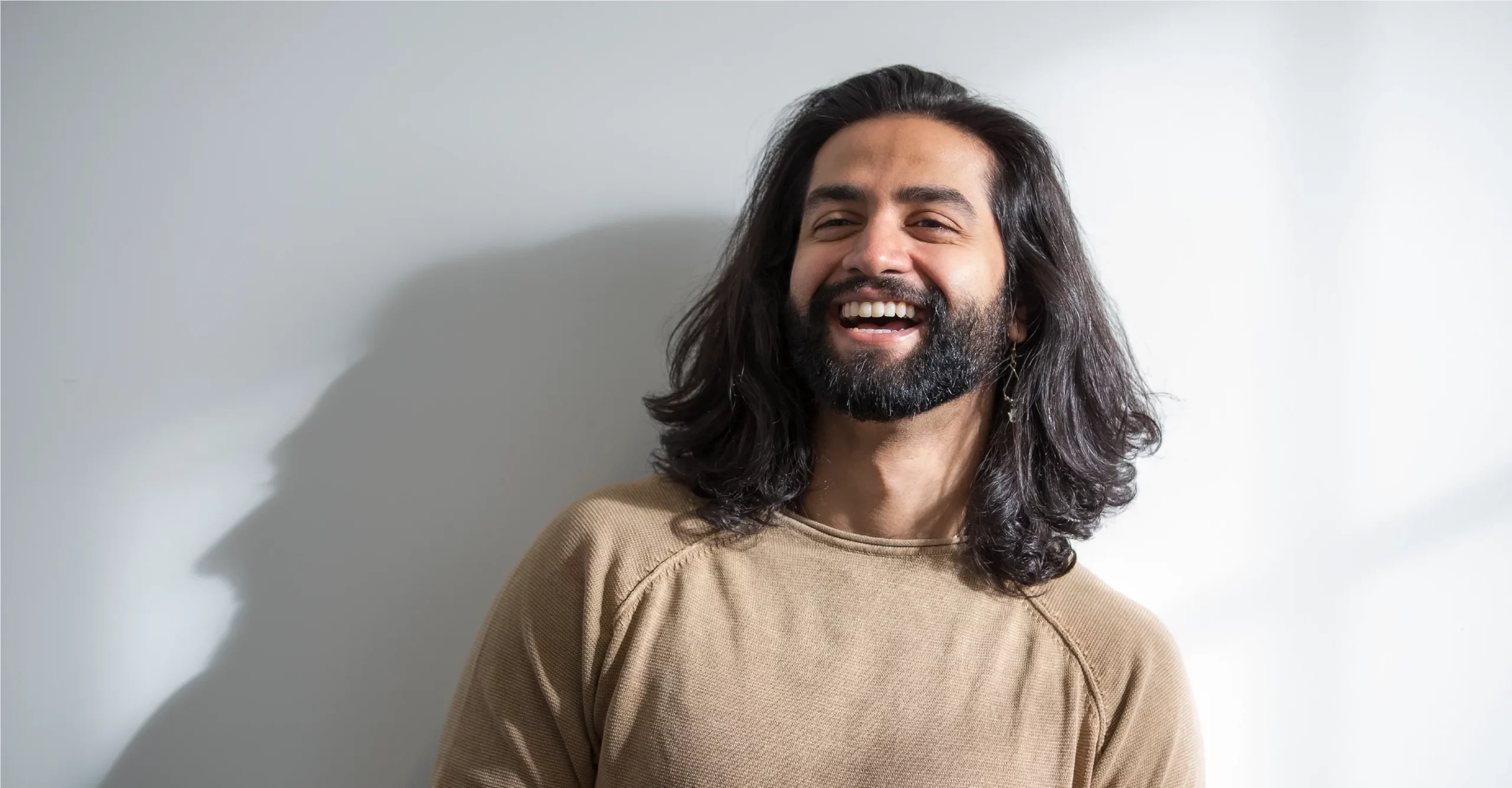 Man with longer grown out hair smiling.