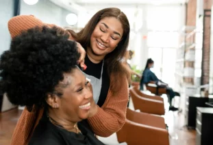 Hair stylist finishing up her client’s natural hair.