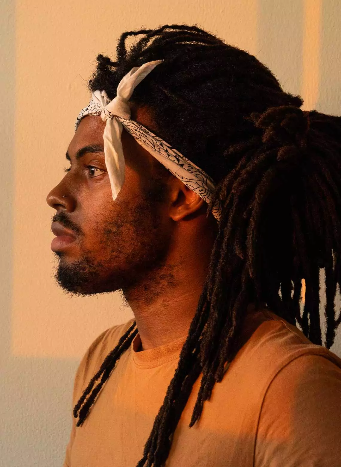 Image of man with locs tied back in a bandana. 