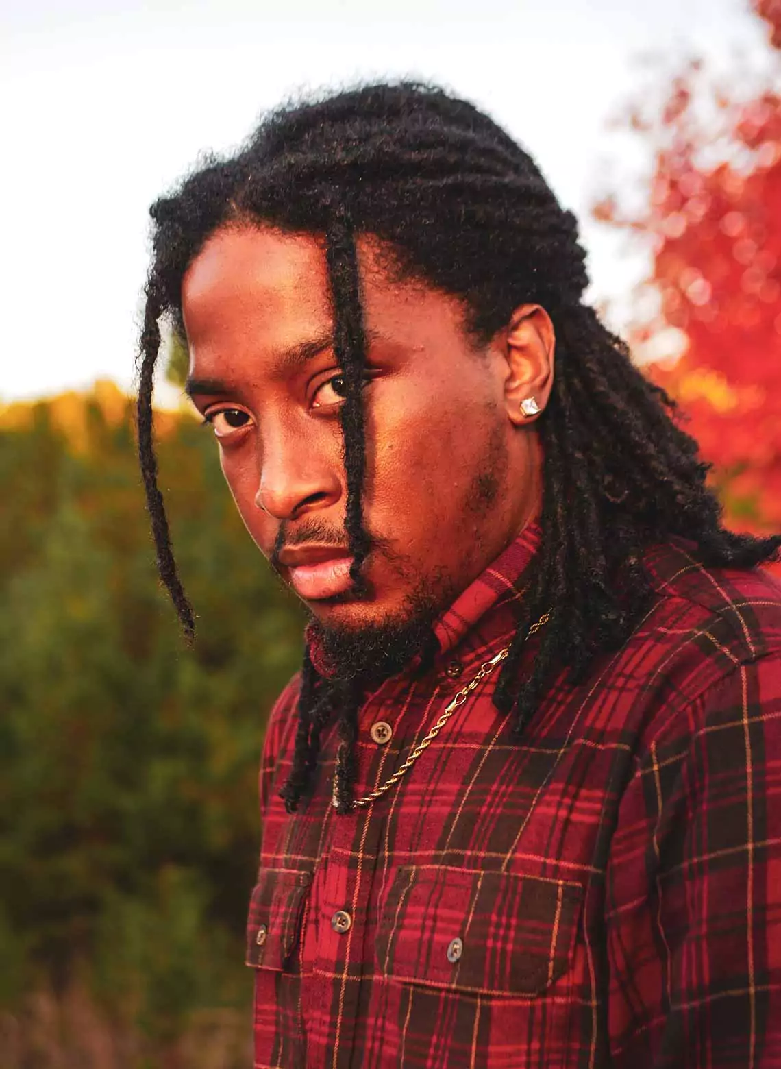Image of man with locs in a half-up, half-down style. 