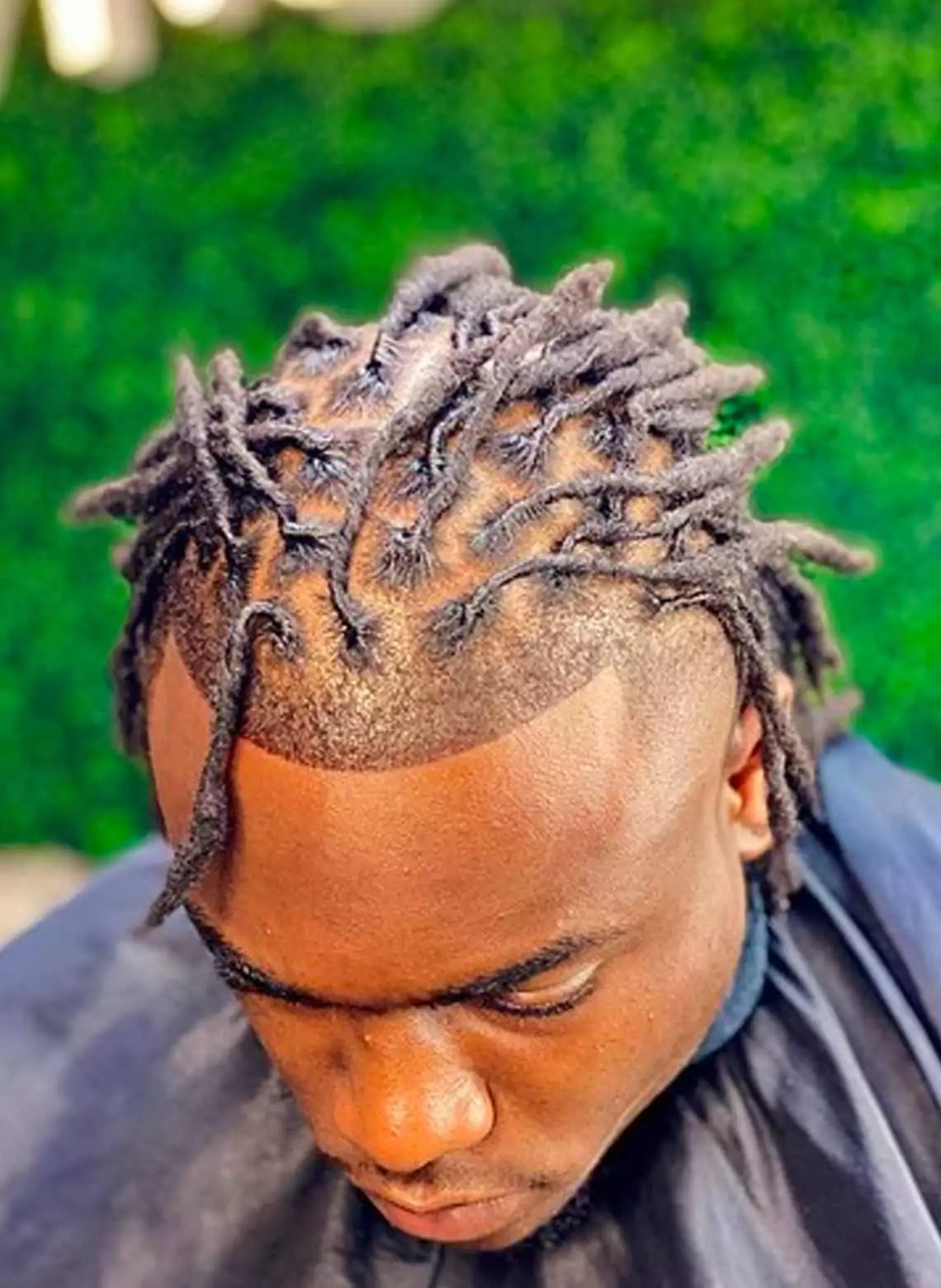 Image of man with shirt locs and a taper. 