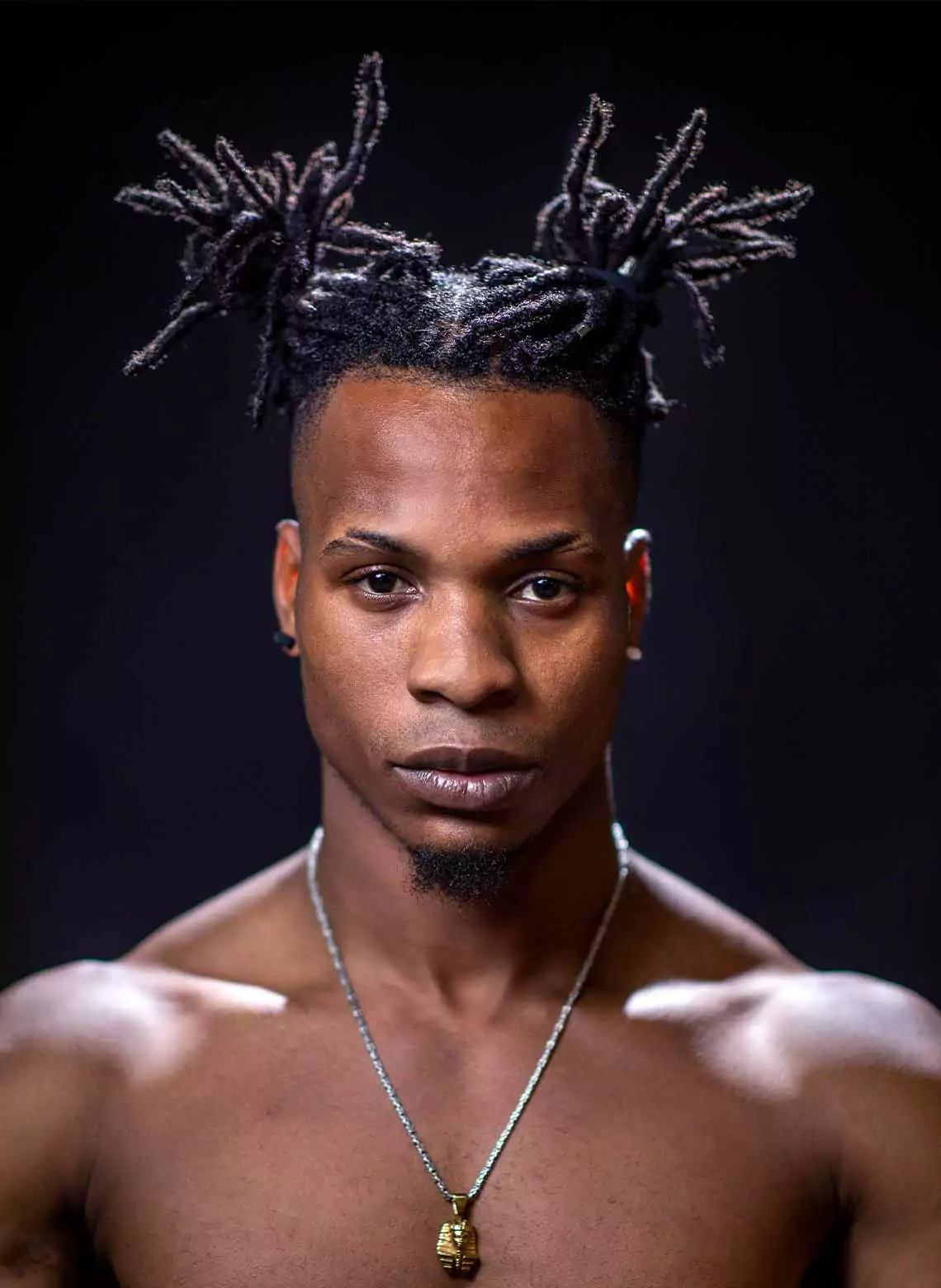 Image of man with locs in space buns. 