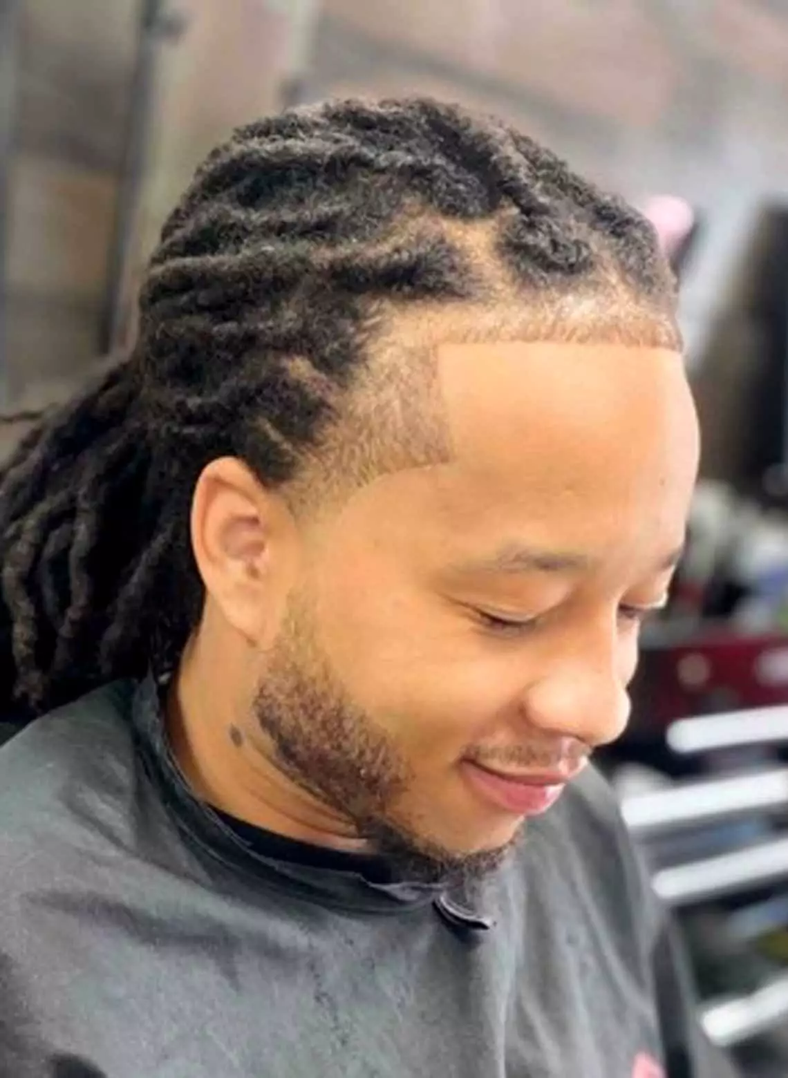 Image of man with locs and a shape-up. 