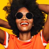 person with natural hair smiling with sunglasses