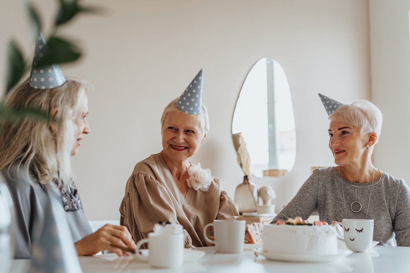 Women wearing party hats and eating birthday cake